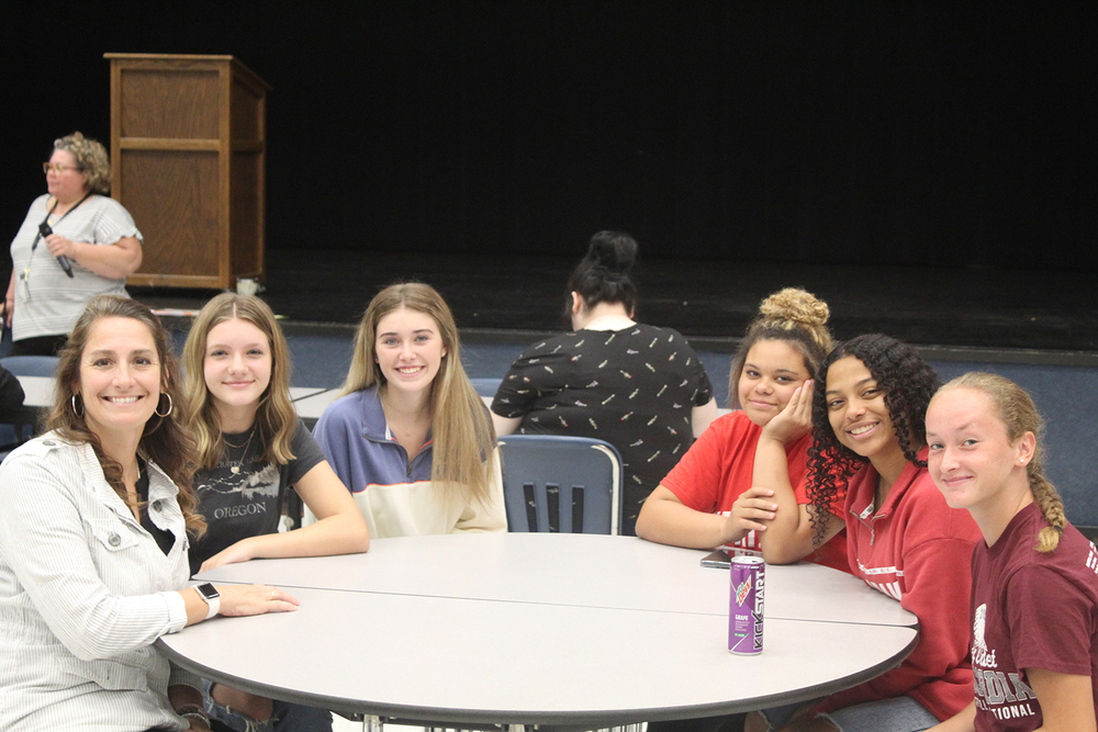 Principal Christensen (far left) sits at a lunch table with 5 Heritage female students.