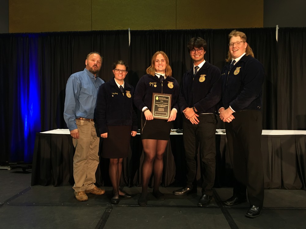 The FFA Farm Business Business Management team stands on stage at the FFA National Convention, including Mr. Shirey, Emily Sorg, Abby Zelt, Wil Rorbach, and Logan Werts.